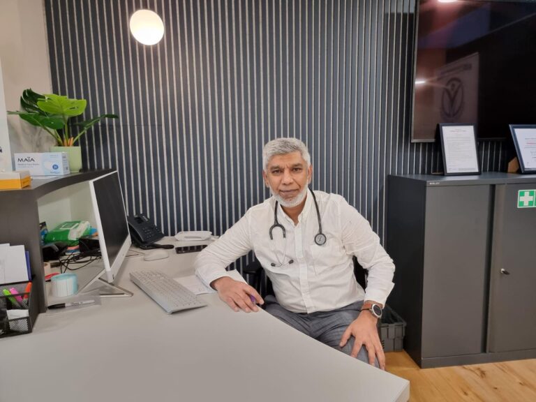 Private GP Smiling and Sitting in his office